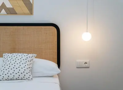 a bed with a white pillow and a light fixture at Estudio Palacios Sur in El Puerto de Santa María