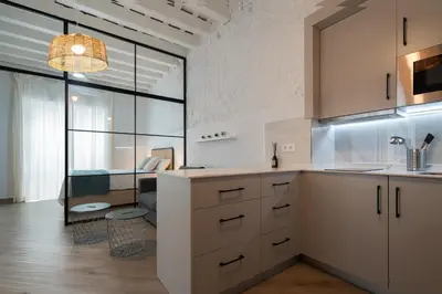 a kitchen with white cabinets and a living room at Estudio Palacios Norte in El Puerto de Santa María