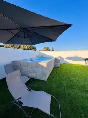 an umbrella and two chairs and a swimming pool at Casa Robin in Conil de la Frontera