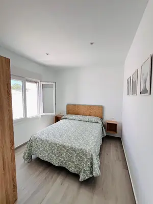 a white bedroom with a bed and a window at Casa Robin in Conil de la Frontera