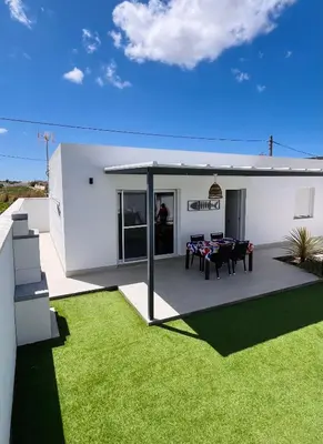 a white house with a patio and green grass at Casa Robin in Conil de la Frontera