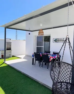 a patio with a table and chairs and a swing at Casa Robin in Conil de la Frontera
