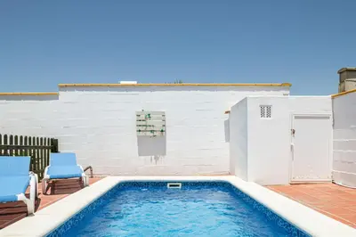 a swimming pool with two blue chairs next to a building at Bellavista De Conil in Conil de la Frontera