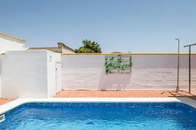 a swimming pool in a backyard with a white wall at Bellavista De Conil in Conil de la Frontera