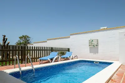 a swimming pool with two blue chairs next to a fence at Bellavista De Conil in Conil de la Frontera