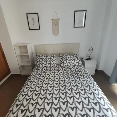 a bedroom with a bed with a black and white comforter at Medina-Sidonia. Apartamento. Carrión y La Zaga in Medina Sidonia