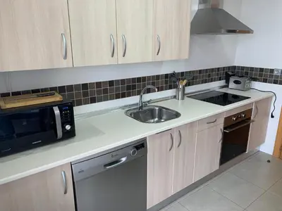 a kitchen with a sink and a microwave at Habitacion privada en piso compartido de dos habitaciones en urbanización con piscina y pista de padel in El Puerto de Santa María