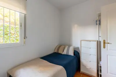 a small bedroom with a bed and a window at Chalet playa la Barrosa, Chiclana in Chiclana de la Frontera