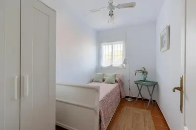 a small bedroom with a bed and a window at Chalet playa la Barrosa, Chiclana in Chiclana de la Frontera