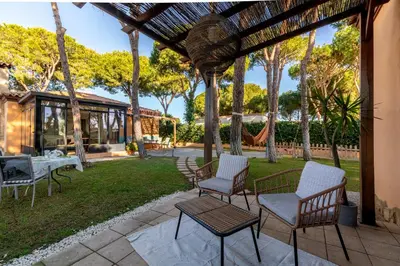 a patio with chairs and a table on a lawn at Chalet playa la Barrosa, Chiclana in Chiclana de la Frontera