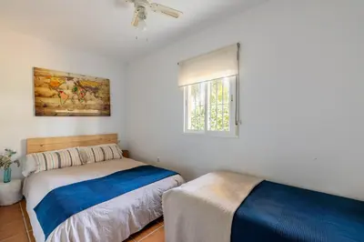 two beds in a room with white walls and a window at Chalet playa la Barrosa, Chiclana in Chiclana de la Frontera