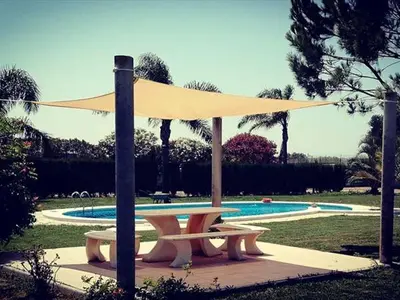 a picnic table with a canopy in front of a pool at Albanta in Chipiona