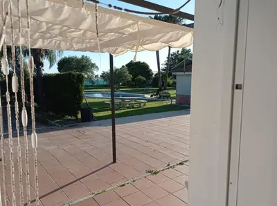 a white umbrella on a patio with a park in the background at Albanta in Chipiona