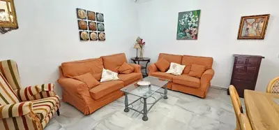 a living room with two orange chairs and a table at Tartaneros Duplex by Sanlúcar Housing in Sanlúcar de Barrameda