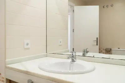a white bathroom with a sink and a mirror at Apartoyou - Estudio Pink in El Puerto de Santa María