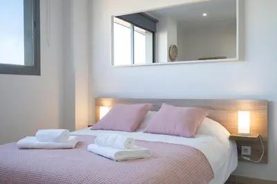 a bedroom with a bed and a table and a kitchen at Apartoyou - Estudio Pink in El Puerto de Santa María