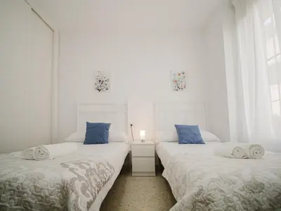 a bedroom with a bed with a white comforter at Sibs Sanlucar Marisma - Renovado Centro Ideal Familias in Sanlúcar de Barrameda