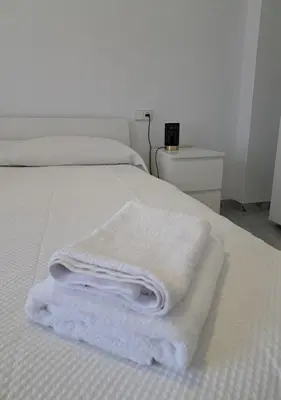 two white towels are stacked on a bed at Encanto Urbano: Piso céntrico totalmente equipado in Lebrija