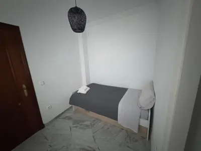 a small bedroom with a bed in a white room at Encanto Urbano: Piso céntrico totalmente equipado in Lebrija