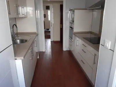 a kitchen with white cabinets and a wooden floor at La Perla de Cádiz by Gades Gestión in Cádiz