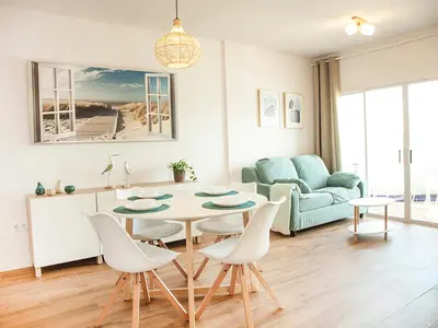 a living room with a table and chairs and a couch at Sanlucarsun Apartamento frente al mar in Sanlúcar de Barrameda