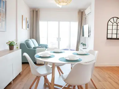 a white dining room with a table and chairs at Sanlucarsun Apartamento frente al mar in Sanlúcar de Barrameda