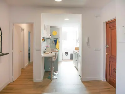 a kitchen with white walls and a table in a hallway at Sanlucarsun Apartamento frente al mar in Sanlúcar de Barrameda