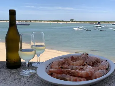a plate of shrimp and two glasses of wine at Sanlucarsun Apartamento frente al mar in Sanlúcar de Barrameda