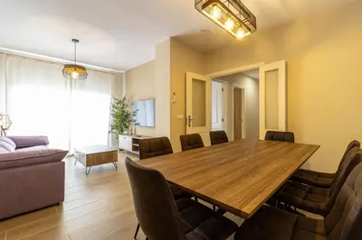 a living room with a wooden table and chairs at Allo Apartments Europa II Parking Piscina Padel 4 Habitaciones in Jerez de la Frontera