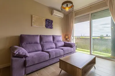 a living room with a purple couch and a table at Allo Apartments Europa II Parking Piscina Padel 4 Habitaciones in Jerez de la Frontera