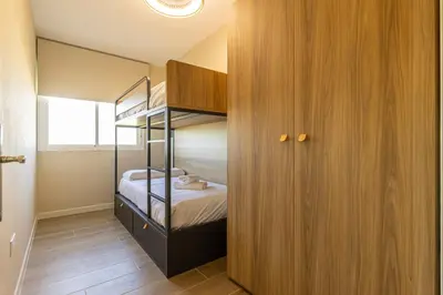 a small bedroom with a bunk bed and wooden cabinets at Allo Apartments Europa II Parking Piscina Padel 4 Habitaciones in Jerez de la Frontera