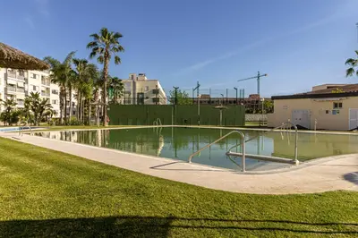 a swimming pool in a park with palm trees at Allo Apartments Europa II Parking Piscina Padel 4 Habitaciones in Jerez de la Frontera