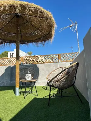 a chair and a table under a straw umbrella at Apartamentos Corredera 2 in Arcos de la Frontera