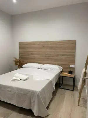 a large bed with white sheets and a wooden headboard at Apartamentos Corredera 2 in Arcos de la Frontera