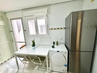 a kitchen with a stainless steel refrigerator and a table at pleno centro con garaje , san Jorge in Sanlúcar de Barrameda