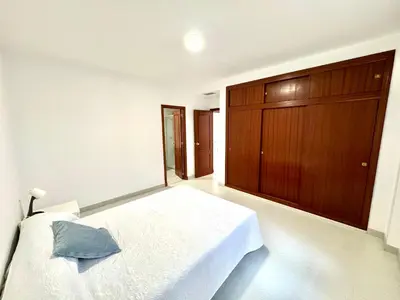 a bedroom with a white bed and a wooden cabinet at pleno centro con garaje , san Jorge in Sanlúcar de Barrameda