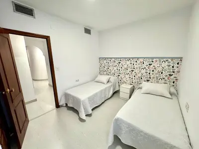 a bedroom with two beds and a mirror at pleno centro con garaje , san Jorge in Sanlúcar de Barrameda