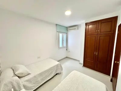 a bedroom with two beds and a wooden cabinet at pleno centro con garaje , san Jorge in Sanlúcar de Barrameda
