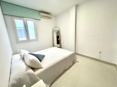 a white bedroom with a bed and a window at pleno centro con garaje , san Jorge in Sanlúcar de Barrameda