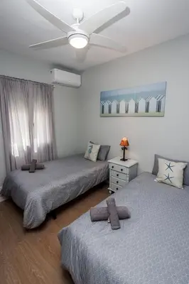 a bedroom with two beds and a ceiling fan at Apartamento Playa Santa María del Mar in Cádiz