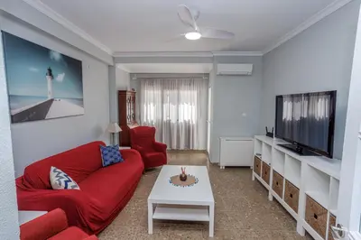 a living room with a red couch and a tv at Apartamento Playa Santa María del Mar in Cádiz