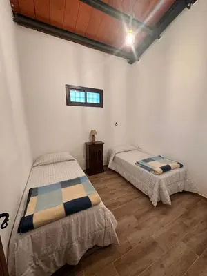 two beds in a room with white walls and wooden floors at Casa Rural Los Murtales in Alcalá de los Gazules
