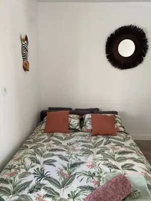 a bedroom with a bed with a comforter and a mirror at ESTUDIO CON TERRAZA CHILL in El Puerto de Santa María