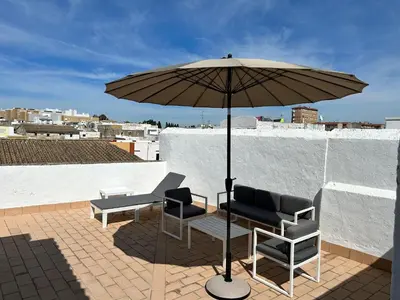 a patio with two chairs and an umbrella on a roof at ESTUDIO CON TERRAZA CHILL in El Puerto de Santa María