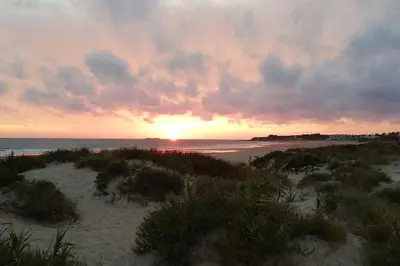 a sunset on a beach with the ocean and the horizon at Apartamento con inmejorables vistas de la Barrosa in Chiclana de la Frontera