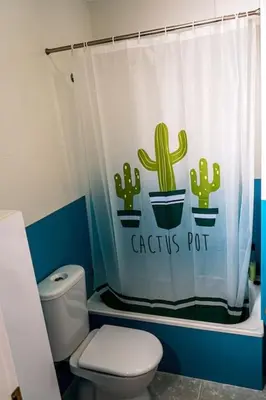 a bathroom with a toilet and a cactus pot shower curtain at Apartamento con inmejorables vistas de la Barrosa in Chiclana de la Frontera