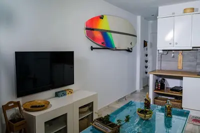 a living room with a flat screen tv and a table at Apartamento con inmejorables vistas de la Barrosa in Chiclana de la Frontera