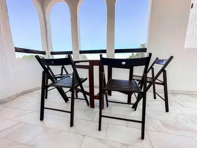 three chairs and a table in a room with windows at Vistahermosa Gestur Apartamentos in El Puerto de Santa María