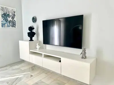 a white entertainment center with a flat screen tv on a wall at Apartment in Plaza Arenal in Jerez de la Frontera