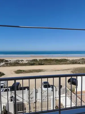 a view from a balcony of a beach with an airplane at Apartamento a pie de playa. in Chiclana de la Frontera